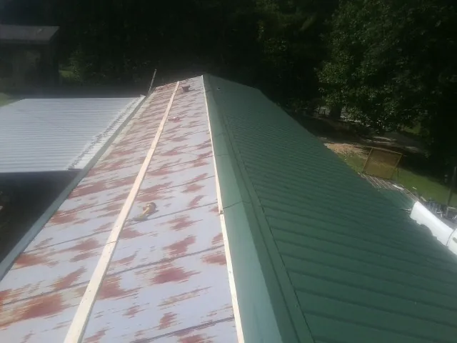 Old rusted panels beside newly installed green metal roofing — Wind Damage Roof Repair by Roofing Brothers in Pearsall