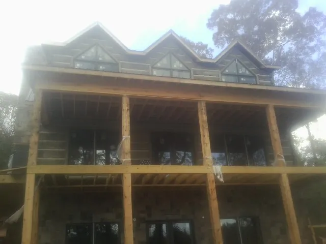 Dormers and porch framing on a large log home under construction — Roof Coating work by our crew in Pearsall