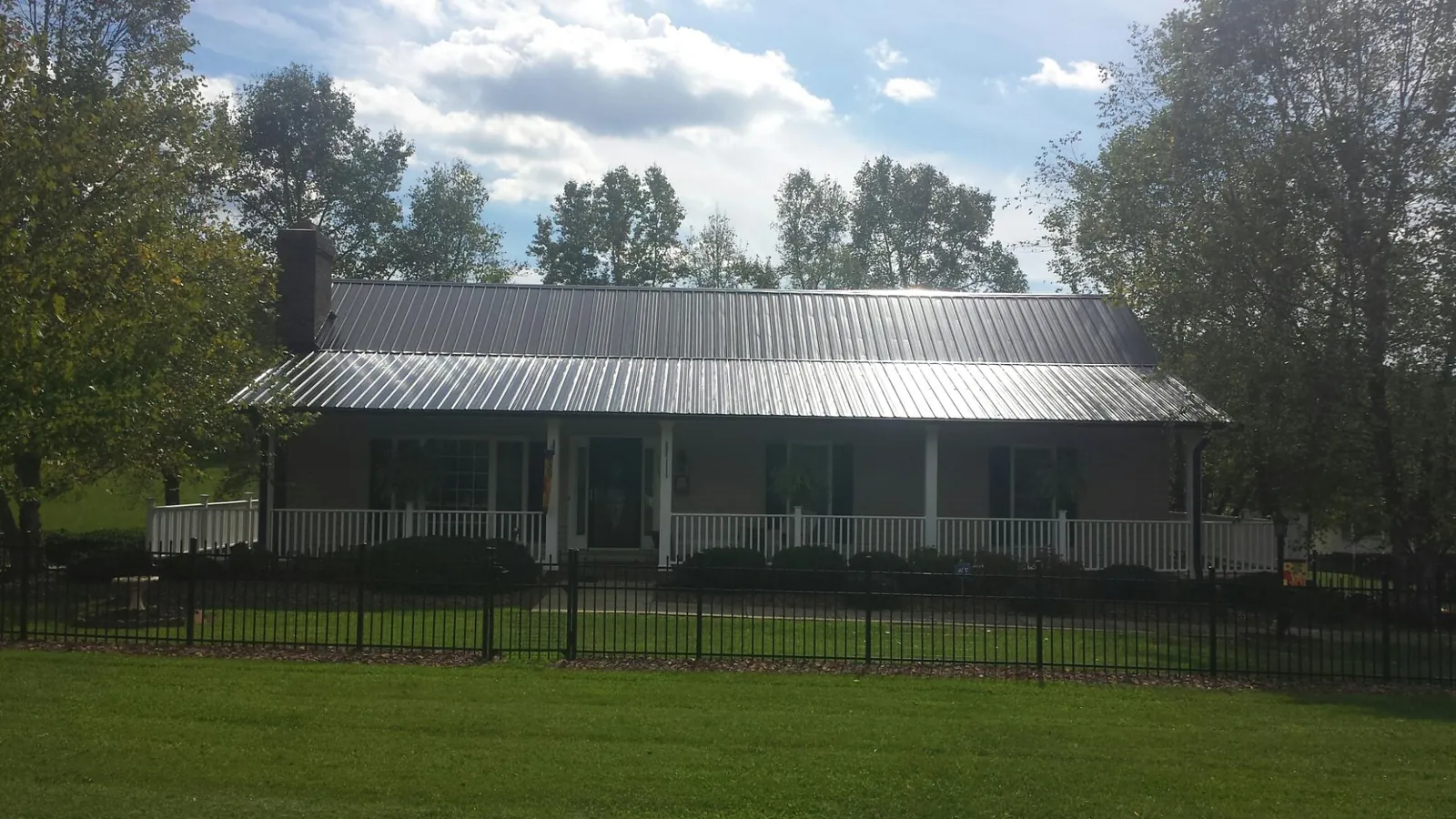 Gray metal roof on a brick ranch with a full width front porch — Gutter Guard Installation work by our crew in Pearsall